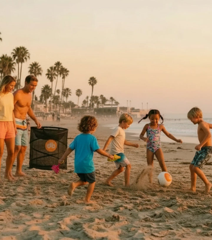 Family playing roundból on the beach at sunset